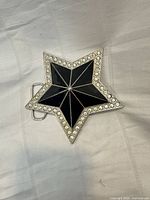 Front view showing star shape, black enamel panels, rhinestone border
