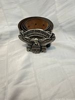 Rolled leather belt front view showing eagle buckle design and inscriptions