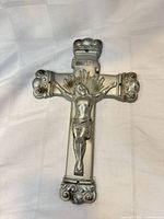 Front view showing corpus, INRI plaque, halo, ornate ends, silver finish