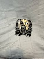 Front view showing skull, crossbones, heraldic shield, scroll border