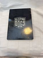 Front of metal SteelBook case showing Sleeping Dogs logo