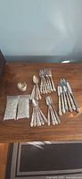 Group shot of all flatware pieces, bowl, and bags of washers on wooden surface