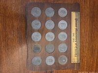 Front view of wooden plaque showing 15 medallions and title plate