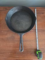 Top view of 10" Levco cast iron skillet with tape measure indicating diameter