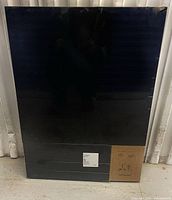 Front view of sealed black table top showing shrink wrap and labels