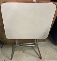 Front view of folded table showing top surface with pattern and red trim