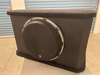 Front view of JL Audio W6 subwoofer in black carpeted box with grill