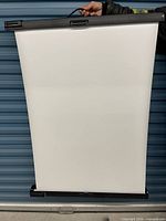 Front view of white projection surface extended from housing with handle visible