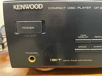Front left view showing Kenwood logo, power button, headphone jack, 1BIT marking