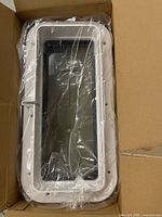 porhole window inside torn box, still in plastic