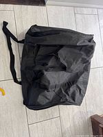 Front view of black round bag lying flat showing zipper and handles