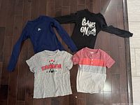 Four shirts laid out showing fronts and designs