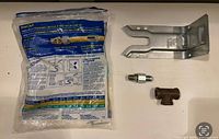 BrassCraft gas connector in sealed bag, steel bracket, compression adapter and tee fitting displayed
