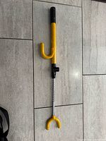 Full view of yellow and black steering wheel lock laid on tile floor