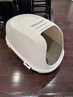 Side view of white hooded cat litter box on hardwood floor