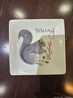 Top view of small square ceramic dish showing squirrel design and "Merry" text