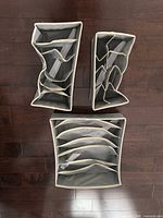 Three gray fabric drawer organizers displayed flat showing compartment layouts