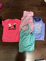 All four girls athletic tops laid out on floor