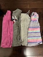 Four sleeveless tops laid flat to show colours, styles and condition