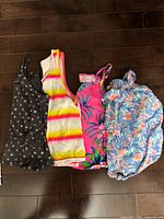 Four children's sleeveless tops laid flat showing front designs