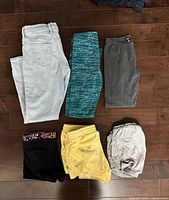 Six clothing items laid out: jeans, leggings, four pairs of shorts