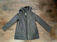 Front view of black hooded coat fully zipped showing overall design and pockets