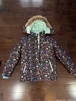 Front view of OshKosh B’gosh winter coat showing multicolour print, hood with faux fur, pockets, zipper
