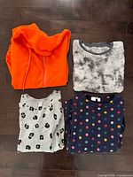 Four folded sweaters showing colours and patterns