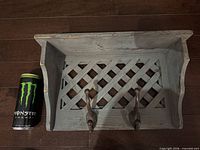 Front view of grey lattice-back wall shelf with hooks and scale can