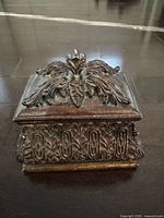 Closed box showing ornate lid and side relief