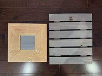 Front view of square wood mirror and gray slatted clipboard
