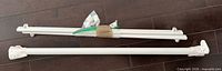 Three bundled white metal rods with attached wall brackets