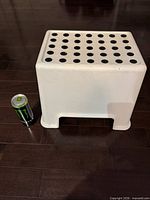 Top view showing black grip dots on white stool next to soda can for scale