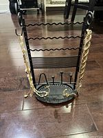 Front view of black metal jewelry stand with gold-tone necklaces and bracelets displayed