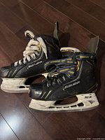 Side view of both Bauer youth hockey skates showing brand logos and Tuuk holders