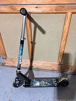 Full view of folding kick scooter showing deck graphics, wheels, handlebar and overall wear