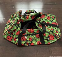 Overall view of ladybug print duffle bag showing shape, pattern, straps and pockets