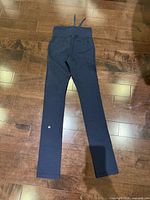 Back view of full-length navy blue pants showing waistband, drawstring ends and reflective logo