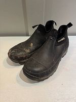 Oblique front view of both boots showing overall design, toe shape, pull loops and dirt wear