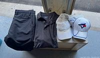 Shorts, polo shirt, two baseball caps on surface