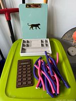 All items grouped on surface: jewelry tray, clipboard, calculator, bundle of hair rollers