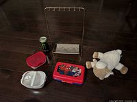 All six items laid out: jewelry stand, plush sheep, two food containers, Spider-Man case, Monster can