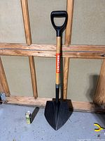 Full view of Craftsman shovel leaning against wall, beverage can for scale