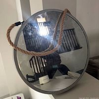 Front view of round mirror showing grey frame and rope hanger
