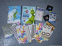 All items in the lot laid out on floor: two Grinch sticker books, baby sticker pack, two photo frame packs, multiple loose sticker sheets