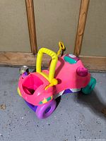 Full view of multicolor toddler ride-on car showing handle, wheels, key, storage compartment