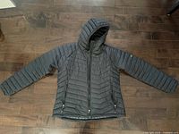 Front view of black Columbia hooded puffer jacket laid flat