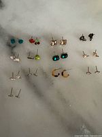 All 13 pairs of earrings laid out on surface