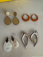 All four pairs of earrings laid out on surface