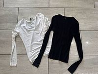 White and black Dynamite long sleeve tops laid flat showing overall design